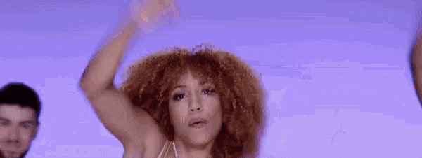 a woman with red hair is dancing in front of a blue background