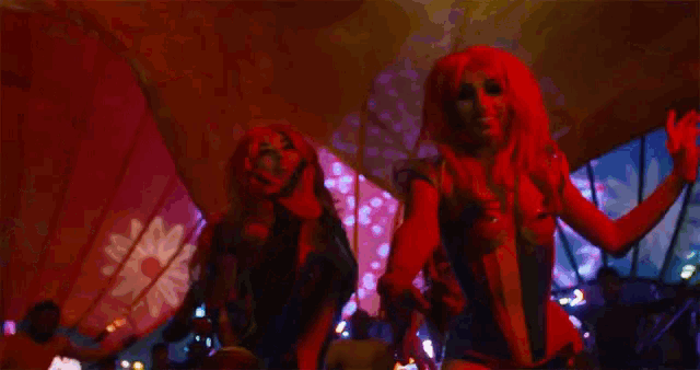 two women in red wigs are dancing in a crowd