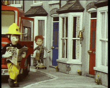 a fireman is reading a newspaper while a little boy rides a scooter