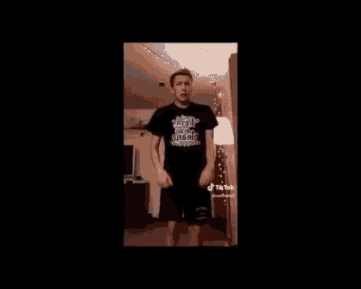 a man in a black shirt and black shorts is dancing in a room .