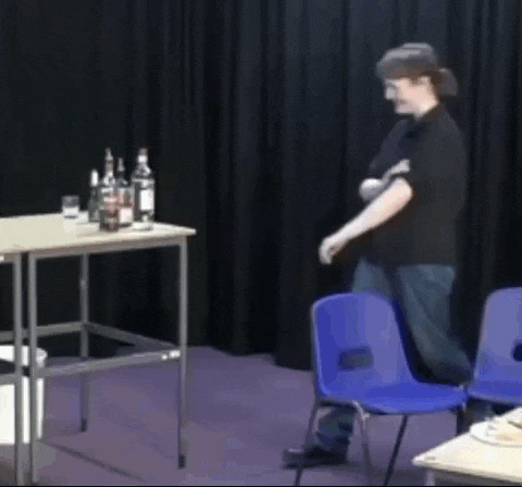 a man in a black shirt is standing in front of a table with bottles on it