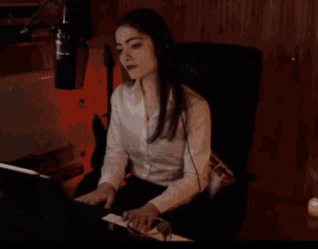 a woman wearing headphones is singing into a microphone in a dark room