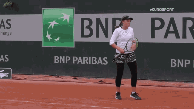 a woman holding a tennis racquet in front of a bnp pariba advertisement
