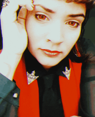 a close up of a woman 's face with a red vest and black shirt