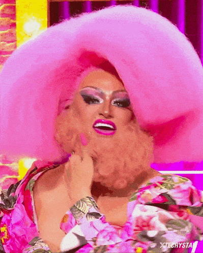 a drag queen with a beard wearing a pink hat