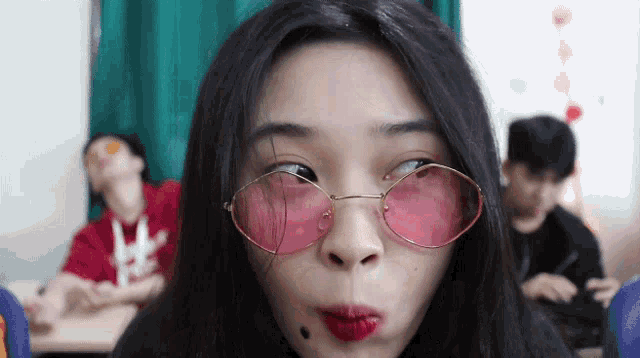 a girl wearing pink glasses is making a face