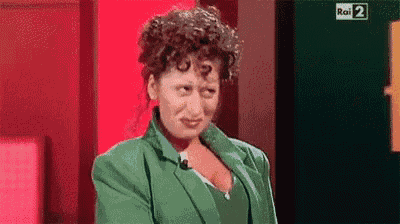 a woman with curly hair is wearing a green jacket and making a face .