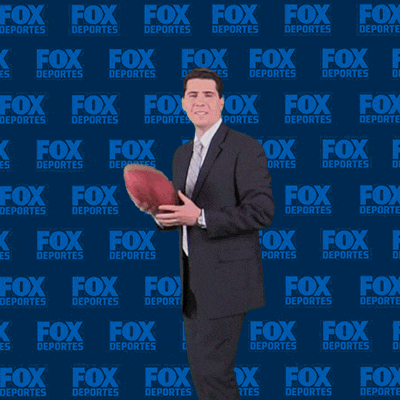 a man in a suit holding a football in front of a fox deportes background