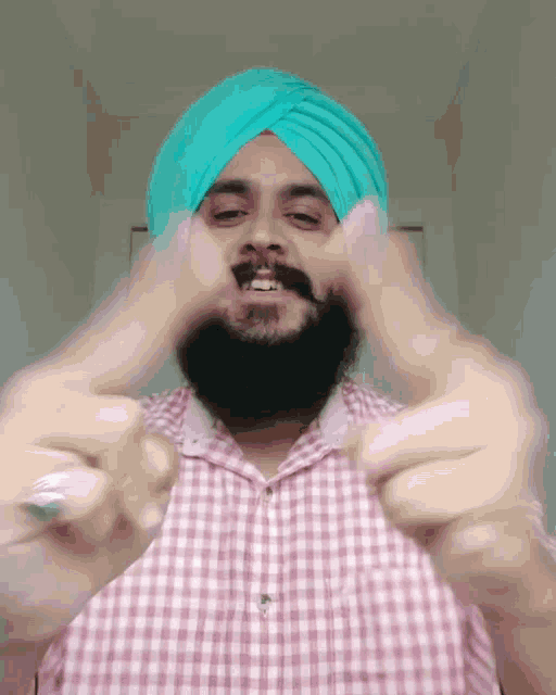 a man with a beard wearing a turban and a plaid shirt is giving the middle finger