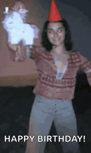 a woman wearing a red party hat is holding a star shaped object .
