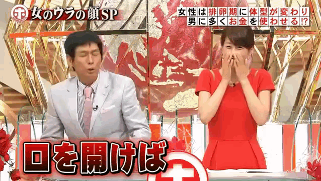 a man in a suit and tie stands next to a woman in a red dress on a tv show in japanese