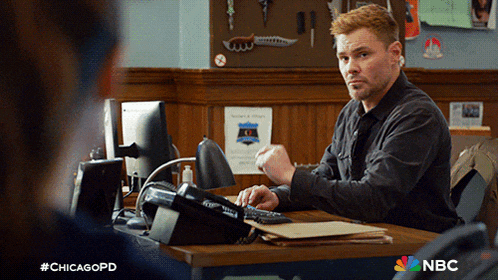 a man sitting at a desk with a nbc logo on it