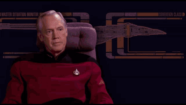 a man sits in a chair in front of a master situation monitor