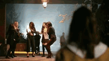 a group of women are dancing in front of a wall