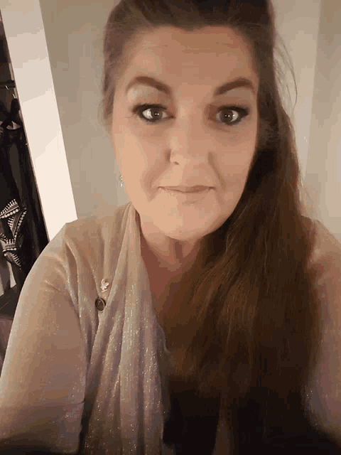 a woman with long brown hair is wearing a sweater and earrings