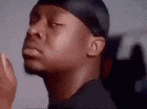 a man wearing a headband and a black shirt is making a funny face with his eyes closed .