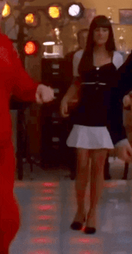 a woman in a black and white dress is dancing with a man in a red jumpsuit