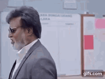 a man with a beard wearing sunglasses and a suit is giving a thumbs up .
