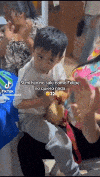 a little boy is sitting on a woman 's lap with a tik tok sticker on the bottom right corner