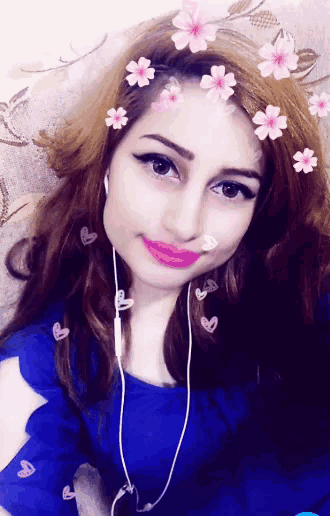 a woman wearing headphones and a blue shirt has flowers in her hair