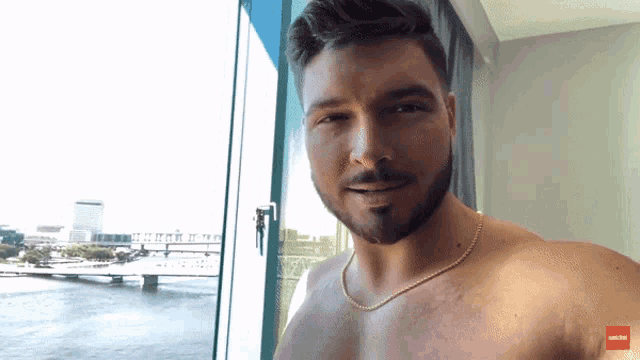 a shirtless man is standing in front of a window with a red arrow pointing to the left that says ' a '