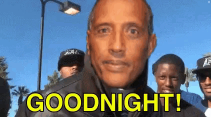 a man in a leather jacket is standing in front of a group of people and saying goodnight .