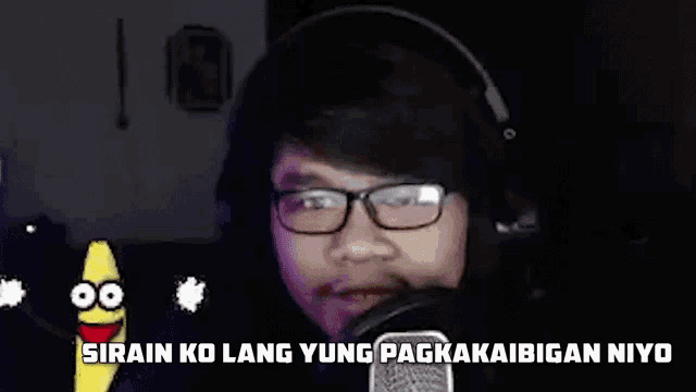 a young man wearing headphones and glasses is talking into a microphone .