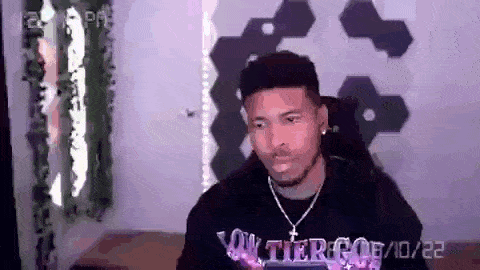 a man is sitting in a chair in a room wearing a sweater that says ' tier ' on it .