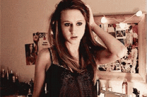 a woman in a black tank top is standing in front of a mirror