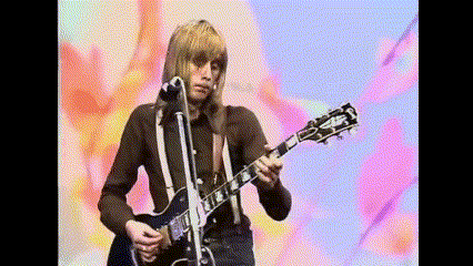 a man playing a gibson guitar in front of a microphone
