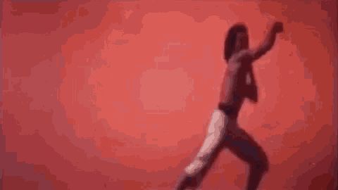 a group of people are walking in a line in front of a red background while a man is jumping in the air .