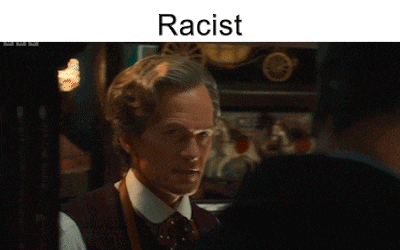 a man in a suit and tie is looking at another man with the word racist above him