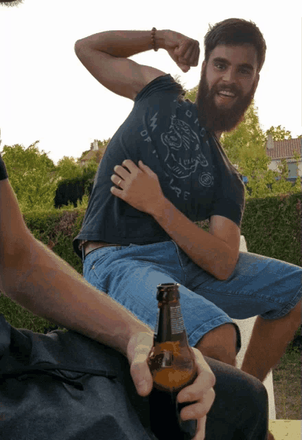 a man with a beard is flexing his muscles while wearing a t-shirt that says " off the wall "
