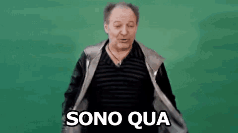 a man in a striped shirt is standing in front of a green background and saying sono qua .