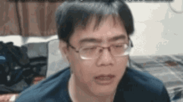a man wearing glasses is making a funny face while sitting on a bed .