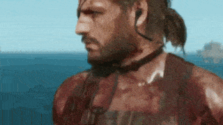 a man with a beard and a ponytail is standing in front of a body of water .