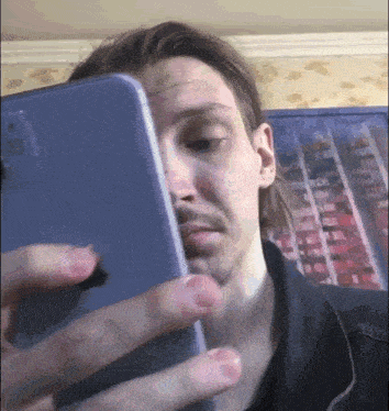 a man with a beard is holding a cell phone to his face .