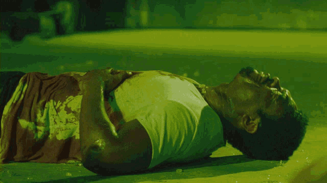 a man in a white shirt is laying on the ground with blood on his shirt