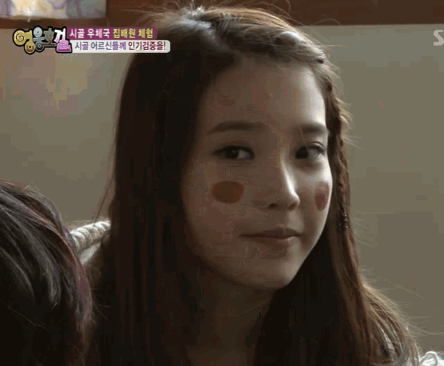 a girl with red circles on her cheeks is looking at the camera