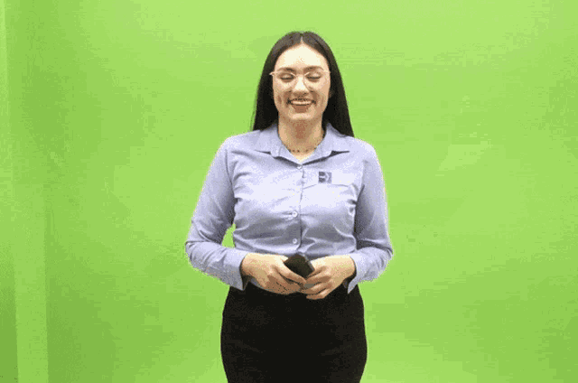 a woman in a blue shirt is holding a remote control and giving a peace sign