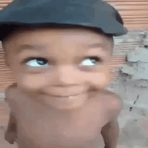 a baby wearing a hat is smiling and looking up .