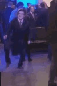 a man in a suit and tie is dancing in a crowd