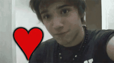 a young man is taking a selfie with a red heart in the background