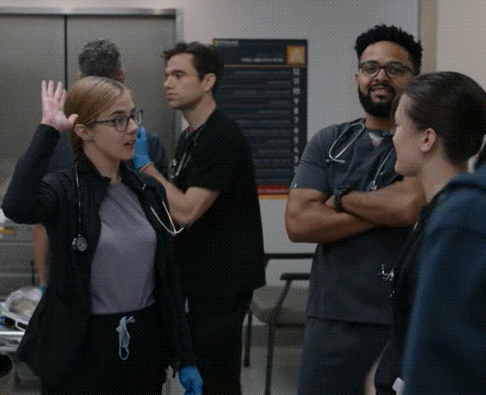 a group of doctors and nurses are standing in a hospital room .