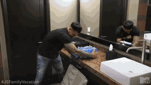 a man is brushing his teeth in a bathroom with a mtv logo on the wall