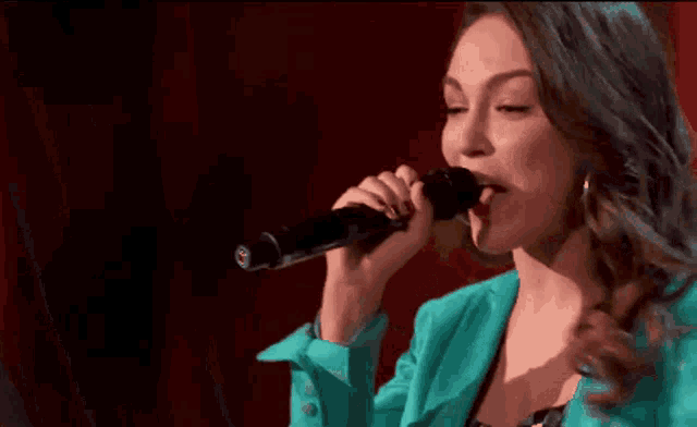 a woman singing into a microphone with a red background