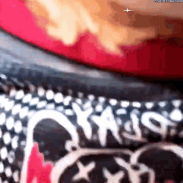 a close up of a person wearing a red shirt with a black and white pattern