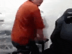 a man in an orange shirt is riding a bike .
