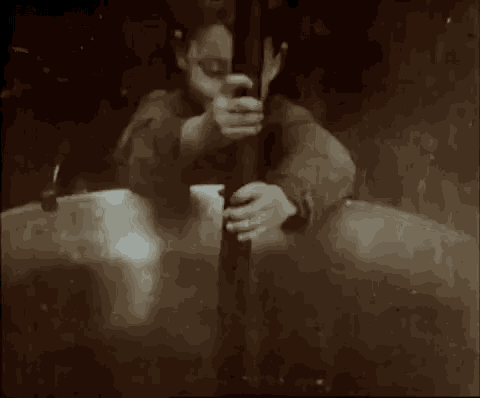 a black and white photo of a person sitting at a table with a book .