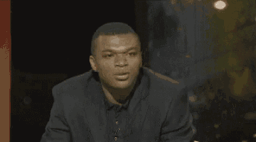 a man is making a funny face with his mouth open in a dark room .